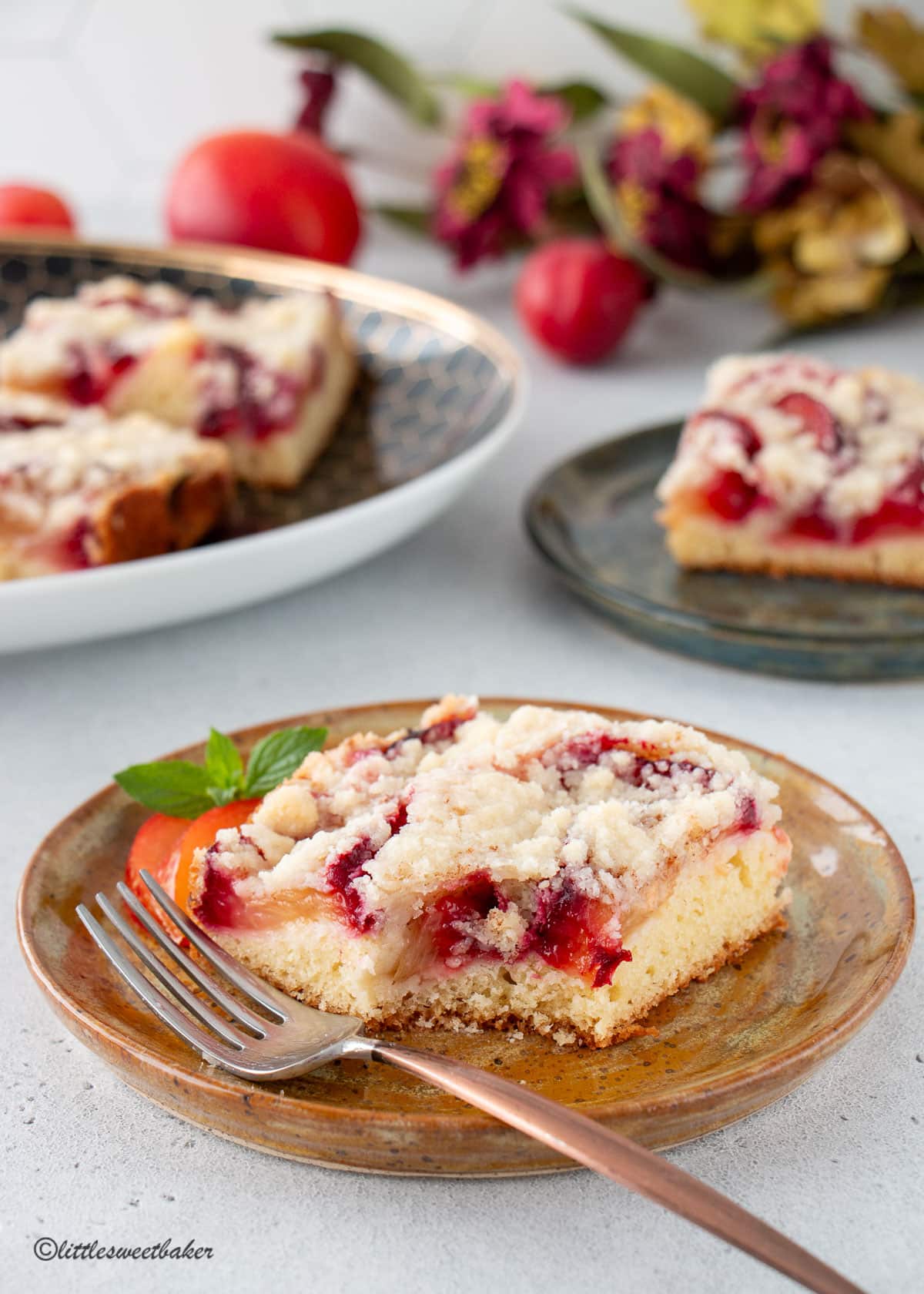 A slice of German plum cake on a plate with a piece missing