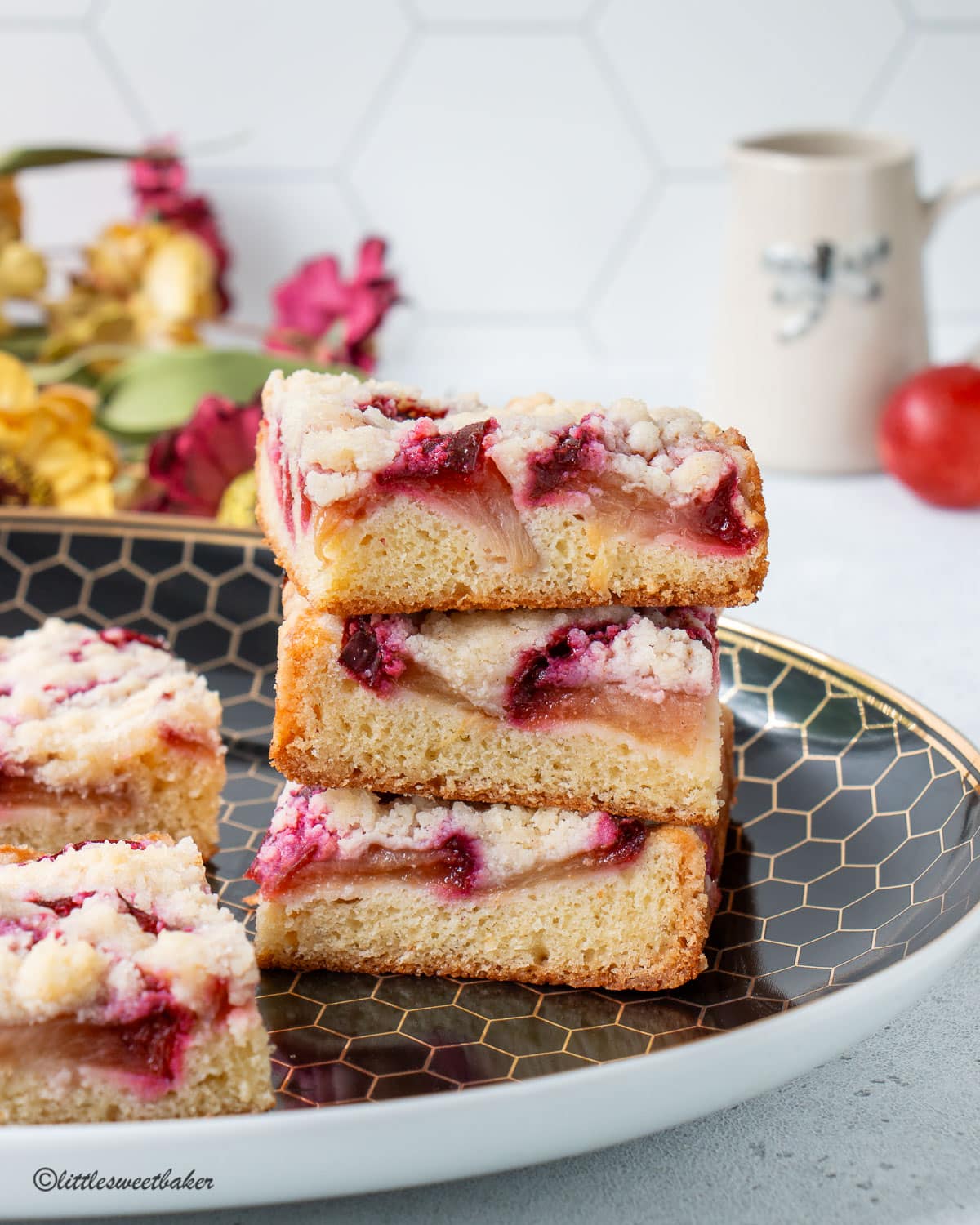 A stack of German plum cake on a black and gold serving plate.