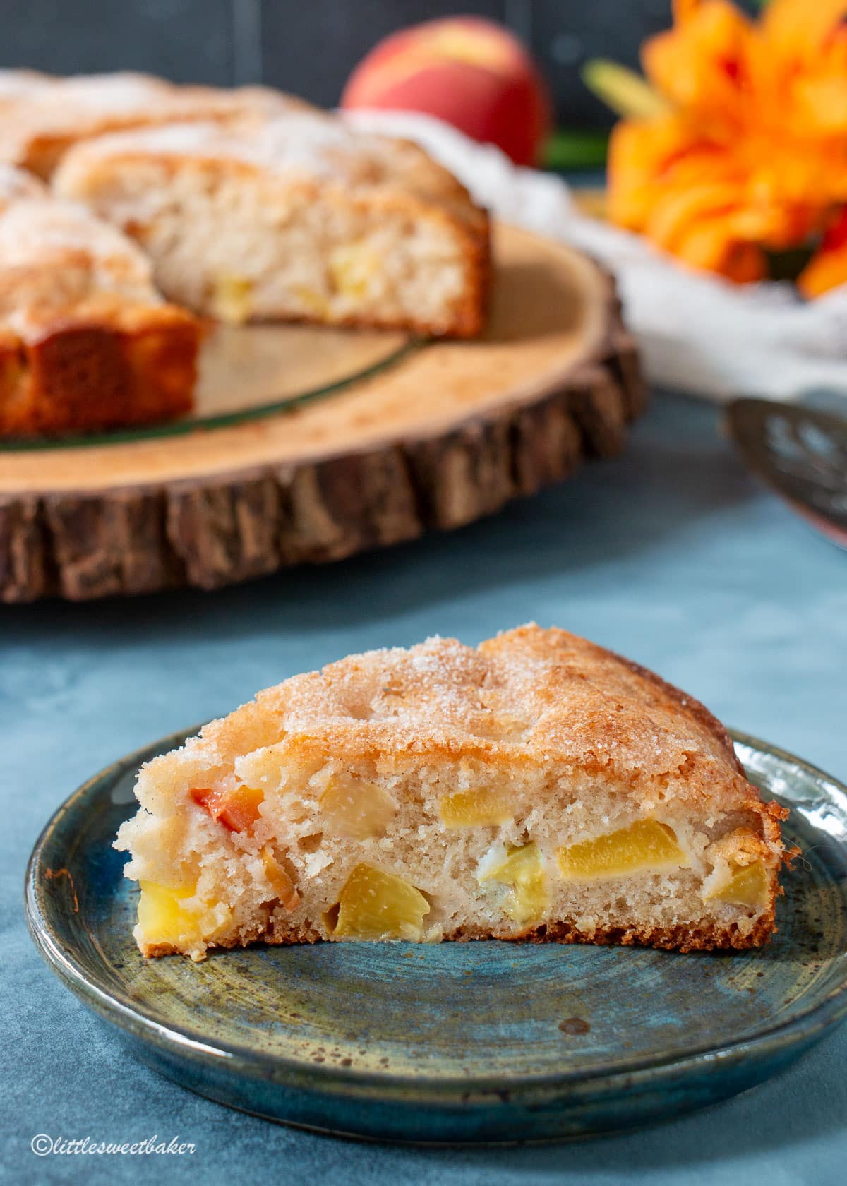 A slice of peach cake on a blue plate.