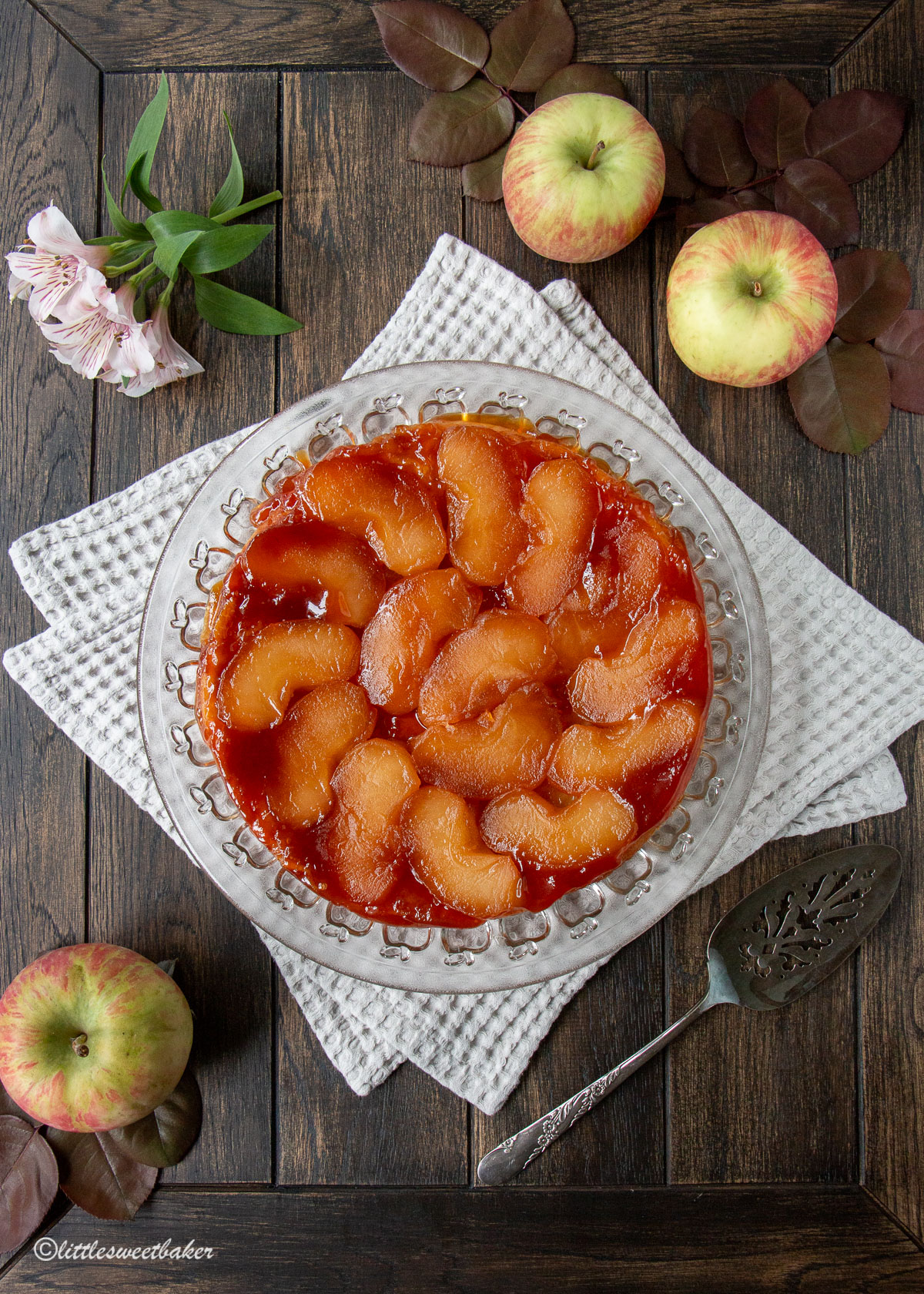 An apple tarte tatin on a clear plate and two gray napkins.