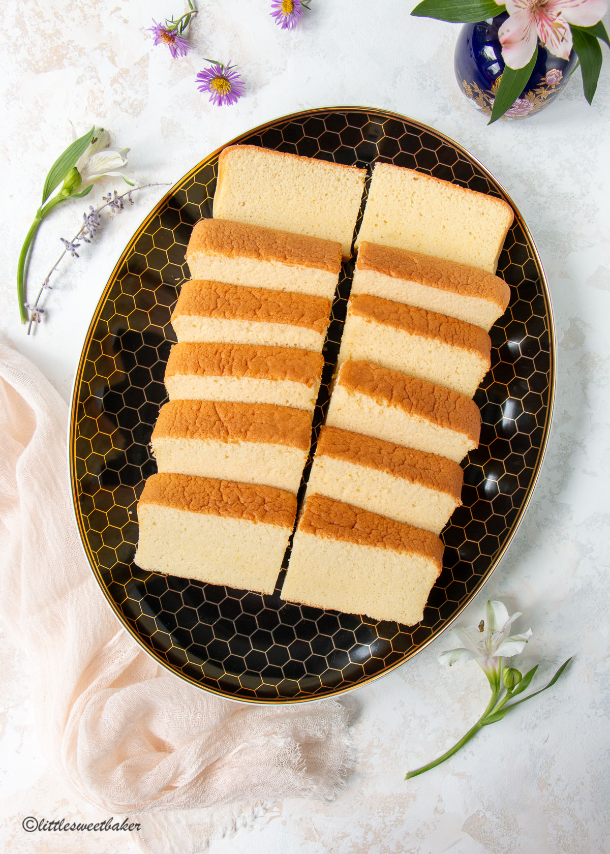 12 slices of castella cake on a black and gold oval plate