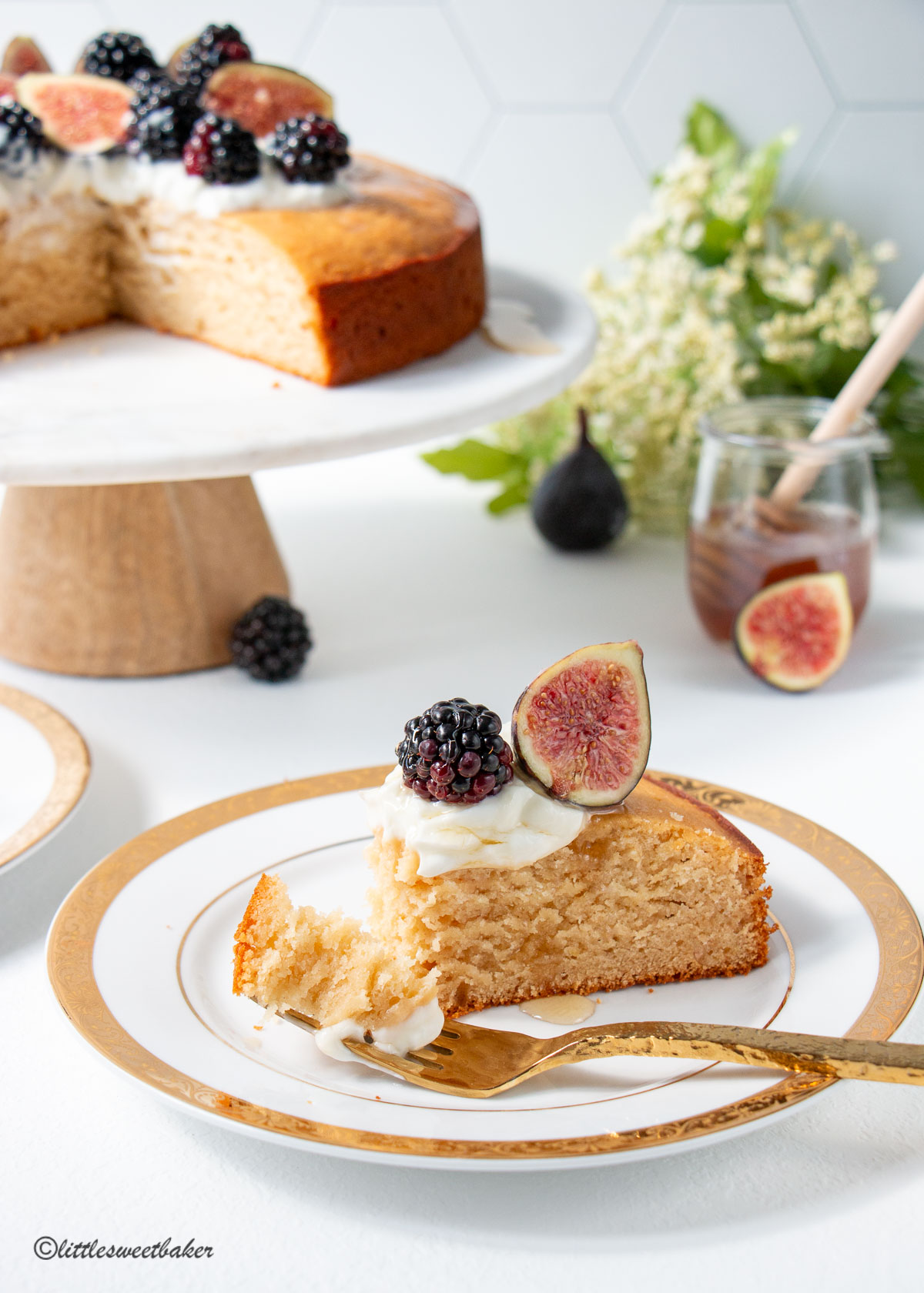 A slice of honey cake topped with yogurt and fruit with a piece on a fork.