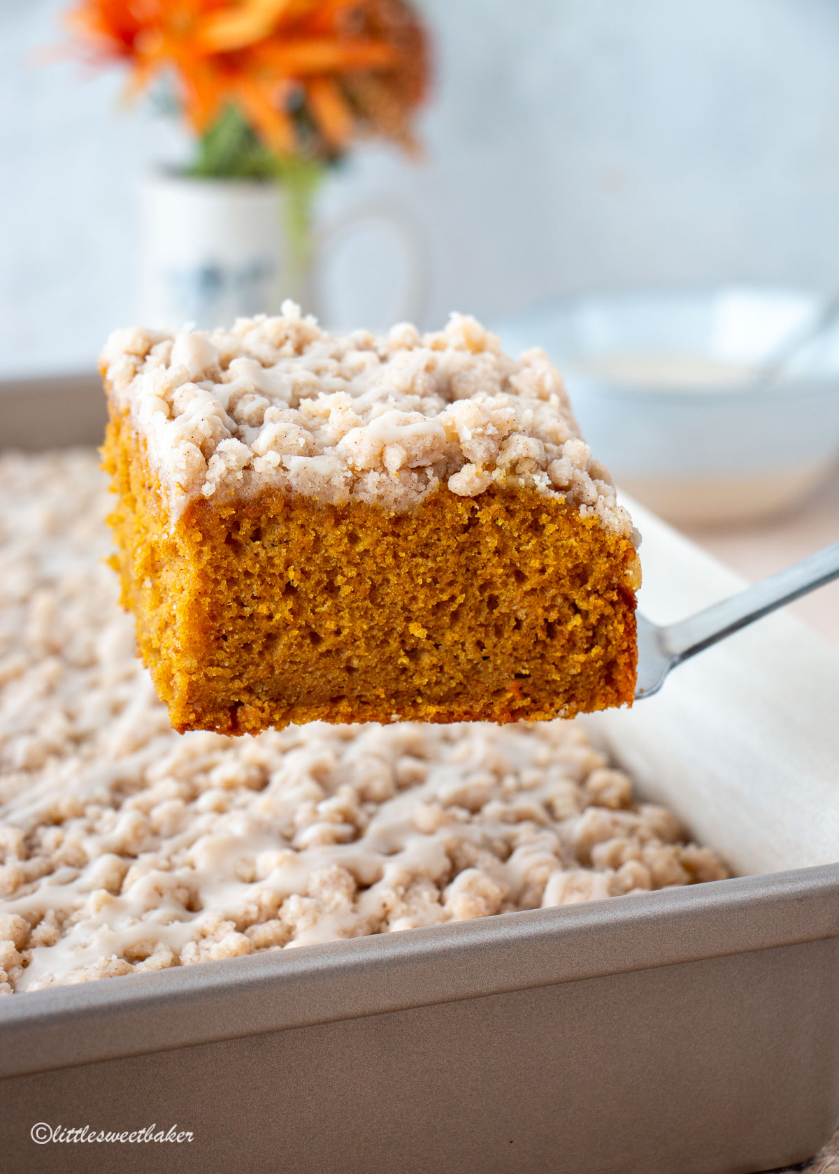 A slice of pumpkin coffee cake being lifted from rest of cake.