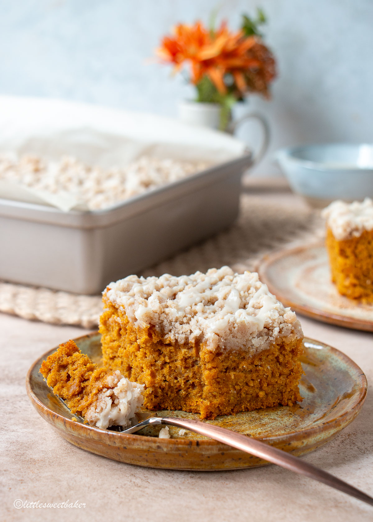 A slice of pumpkin coffee cake on a plate with a piece on a fork.