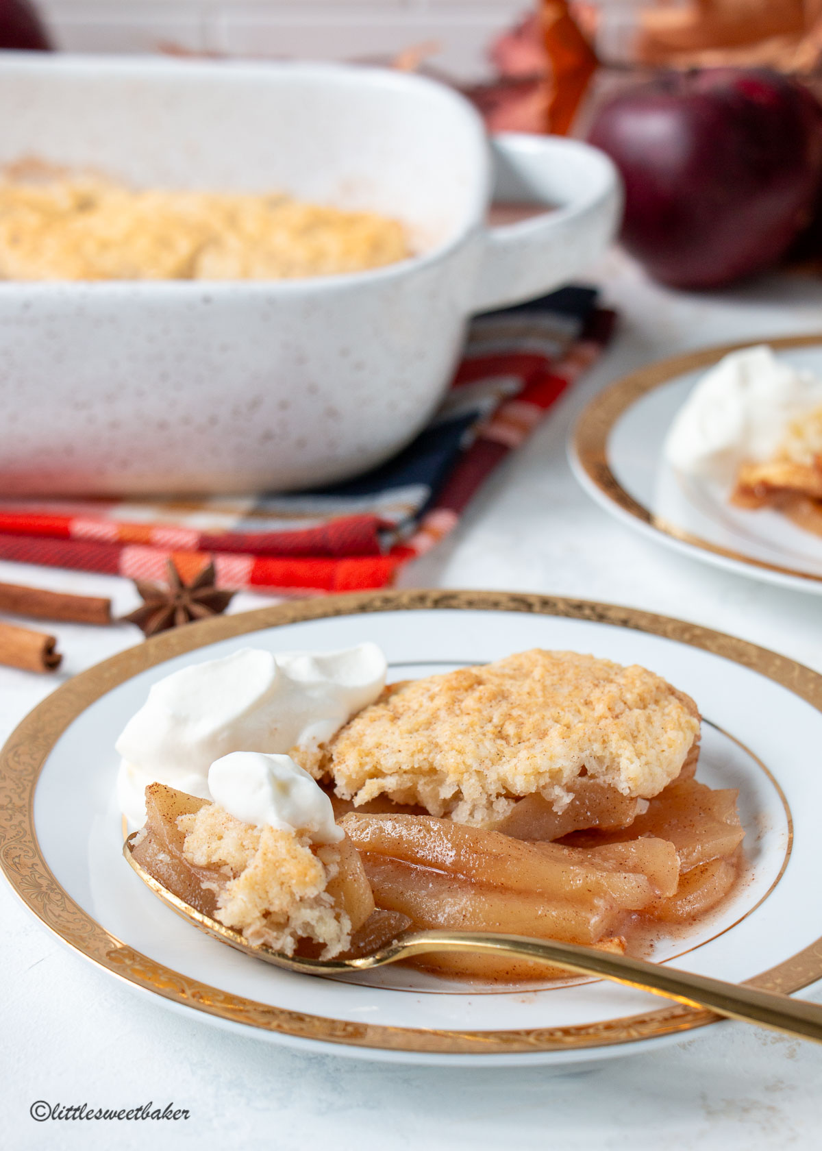 Apple cobbler with whipped cream on a plate with some on a spoon.