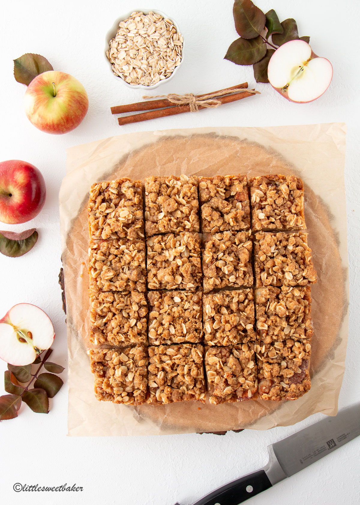 Overhead view of apple crisp bars on a sheet of parchment paper and wooden board.
