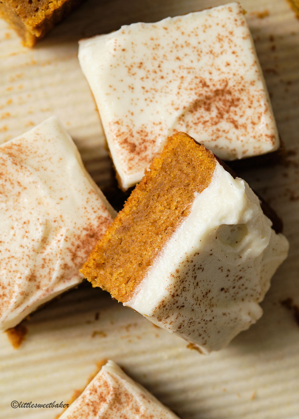 A close up of a pumpkin bar with cream cheese frosting and light dusting of cinnamon.