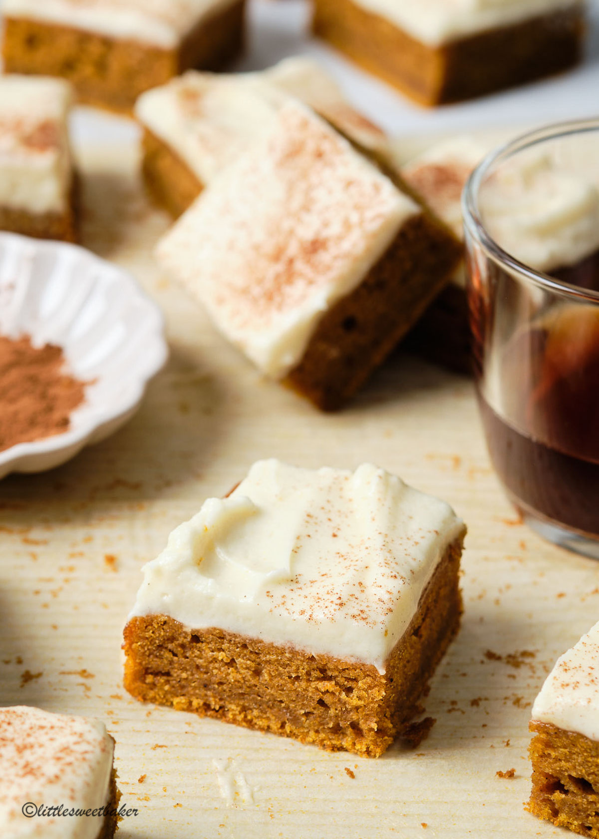 pumpkin bars with cream cheese frosting scattered on a sheet of parchment paper