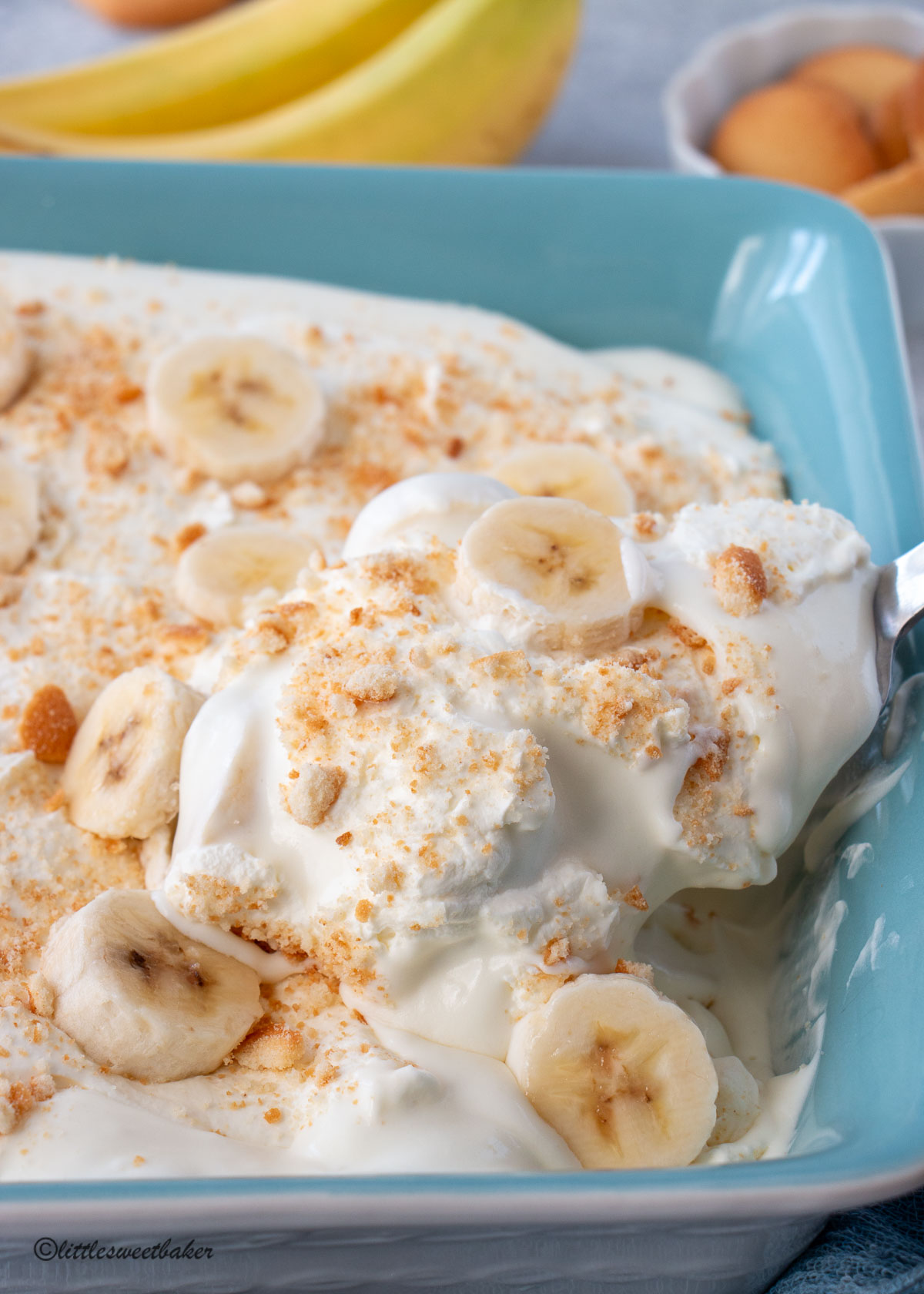 A serving spoon of banana pudding being removed from a casserole dish.