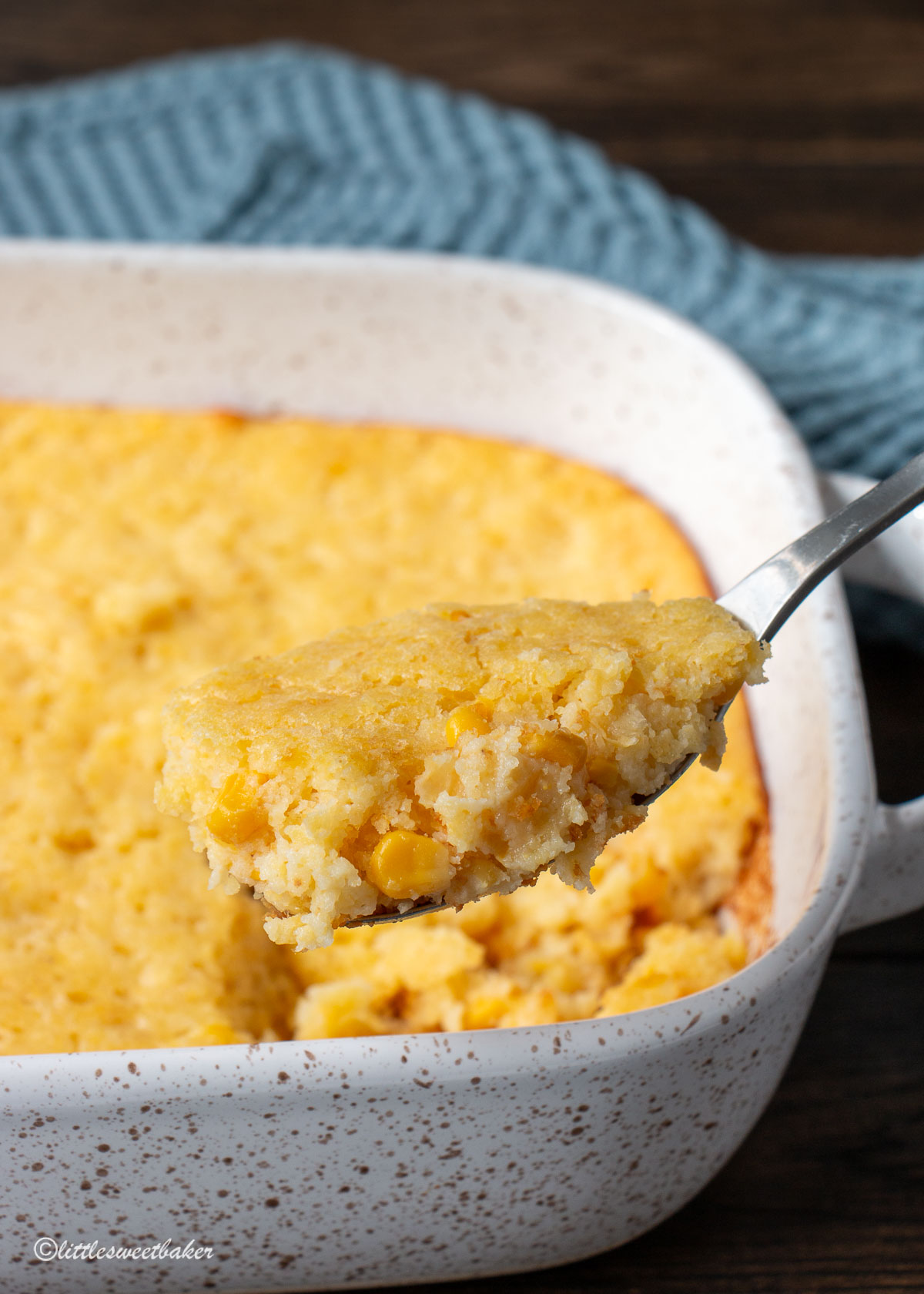 A spoonful of corn casserole being lifted from the casserole dish.