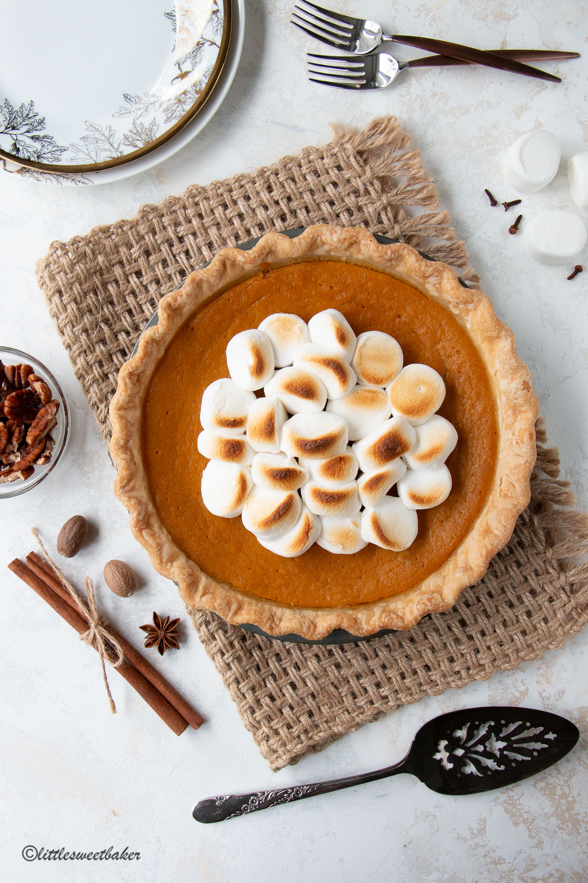 A sweet potato pie topped with toasted marshmallows on a piece of burlap.