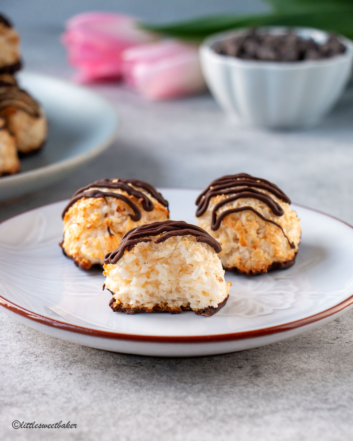 three coconut macaroons on a plate with a bite taken out of one