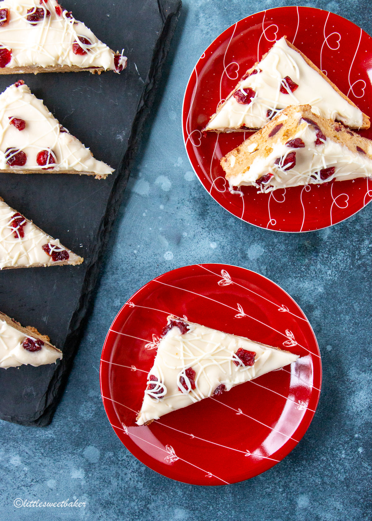 cranberry bliss bars on red plates on piece of black slate