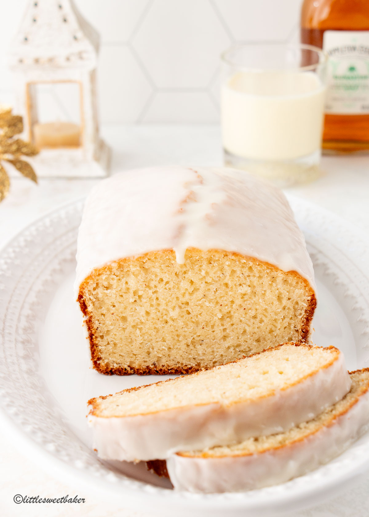 A loaf of eggnog bread with rum glaze on a white serving plate