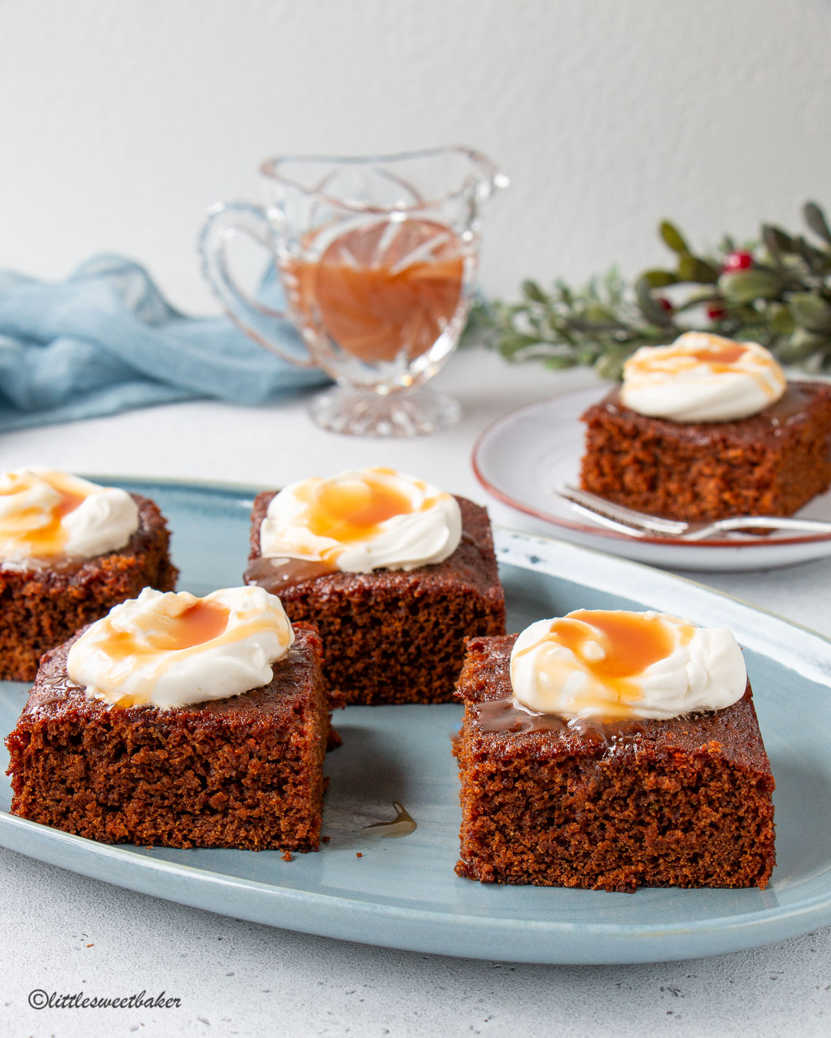 Slices of gingerbread cake with whipped cream and caramel on a blue serving plate