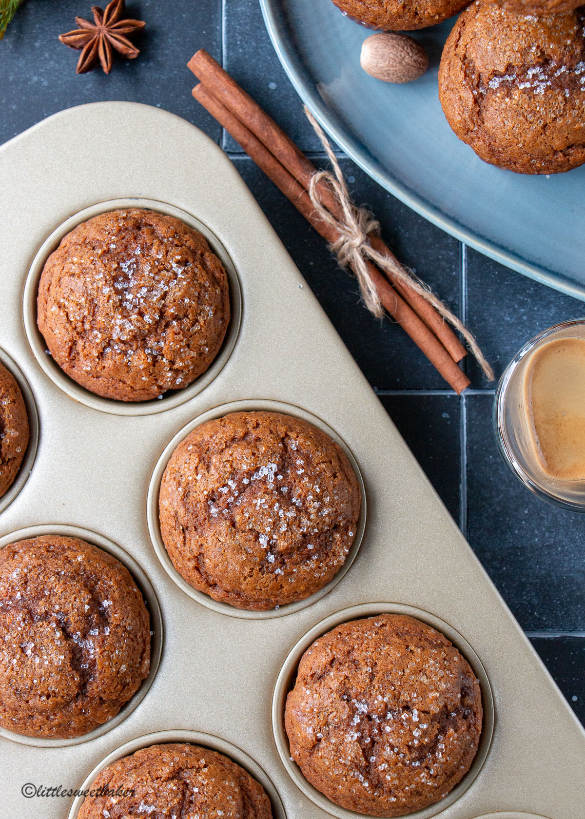 Overhead view of gingerbread muffins in a gold muffin pan and some on a blue plate.