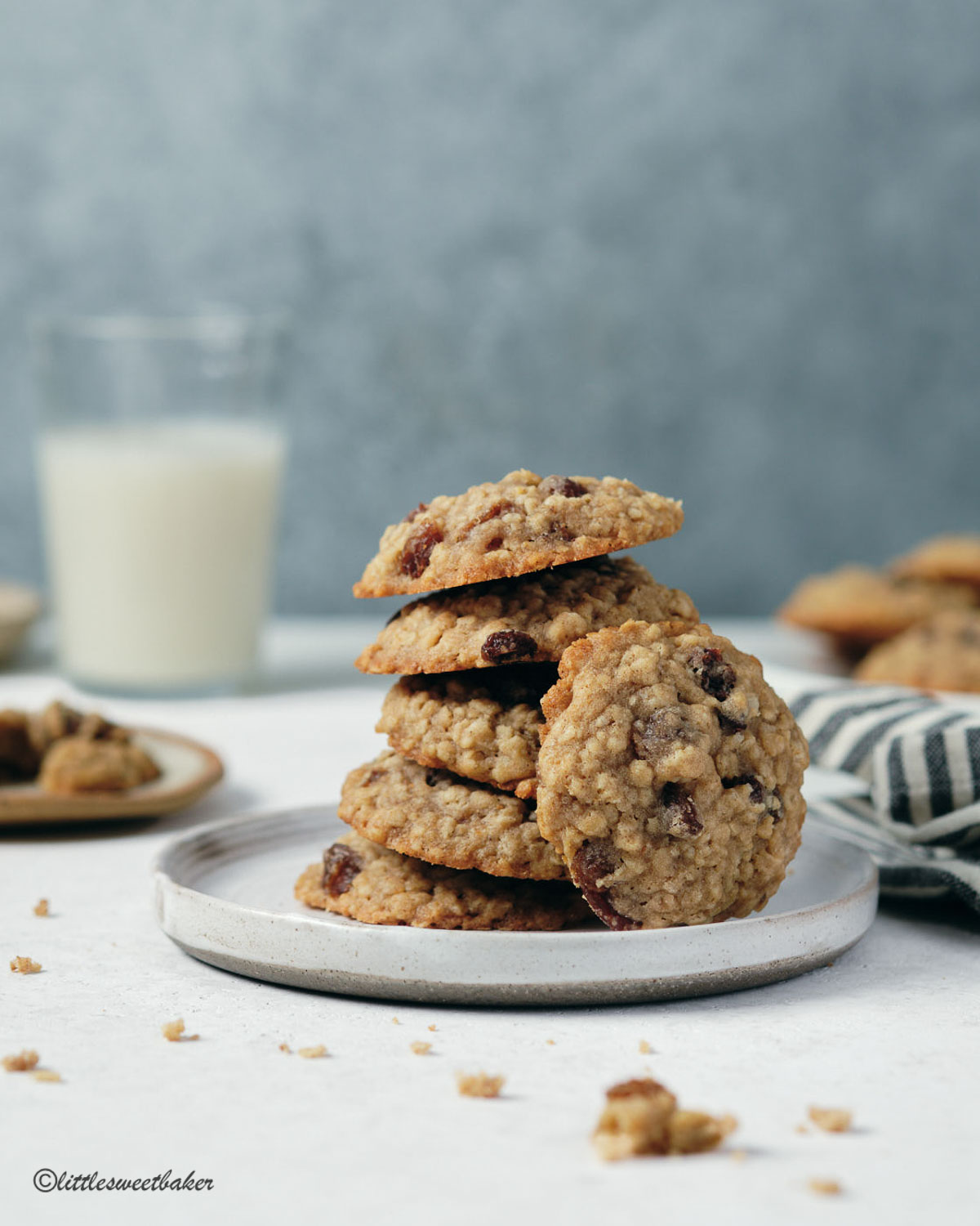 A stack of oatmeal raisin cookies on a plate with one on it's side.