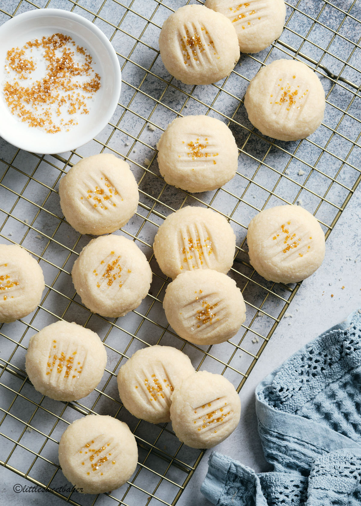 Whipped shortbread cookies scattered on a gold cooling rack.