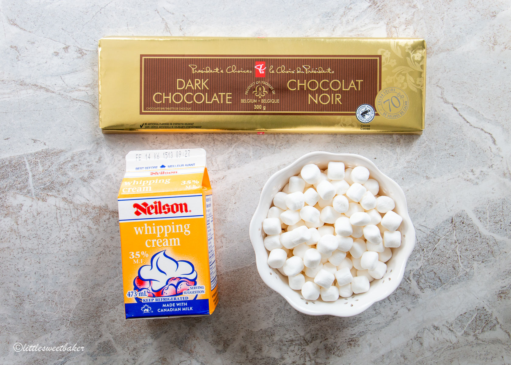 ingredients for easy chocolate mousse: a dark chocolate bar, a carton of whipping cream, and a bowl of mini marshmallows