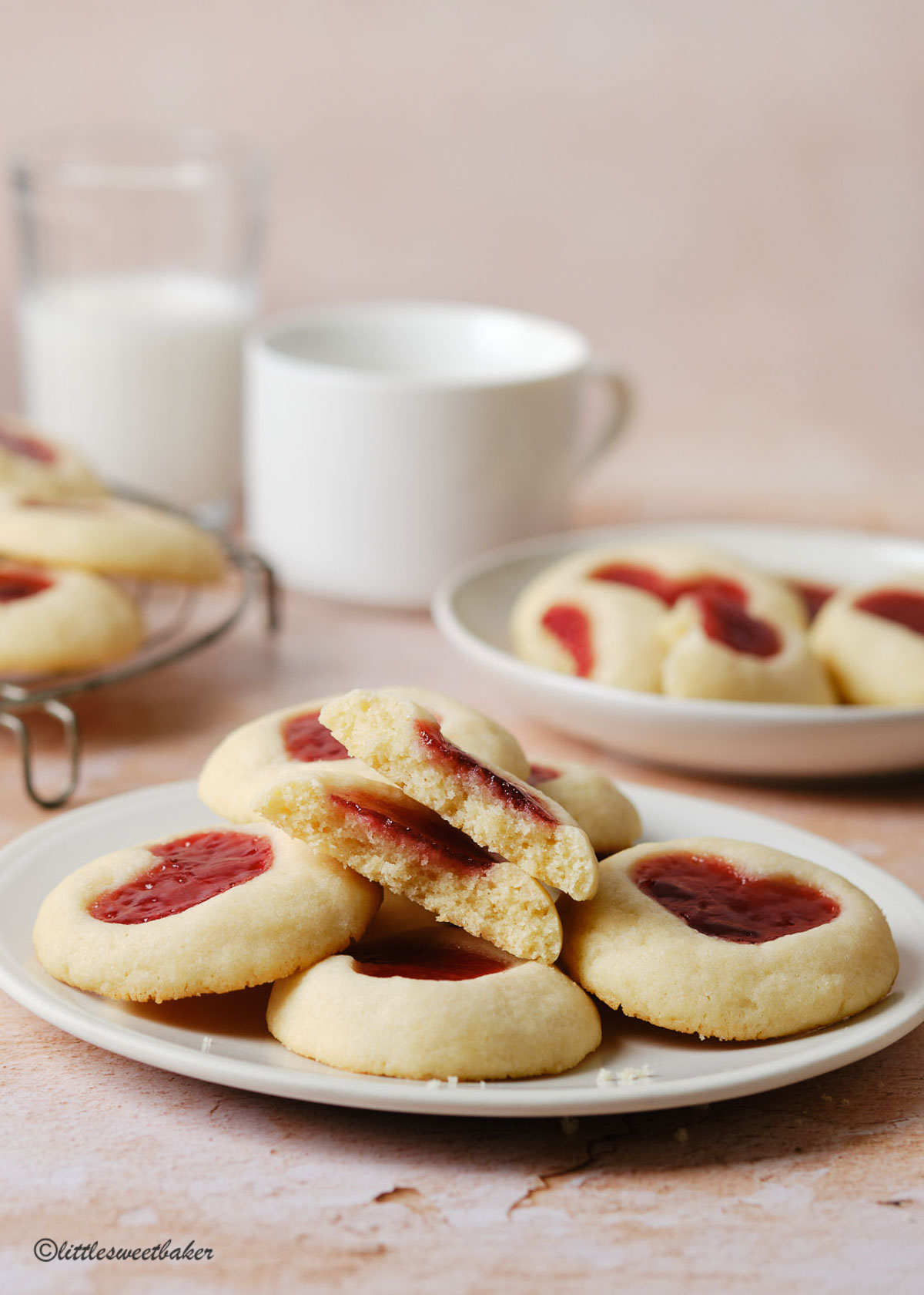 strawberry thumbprint cookies on a plate with one broken in half