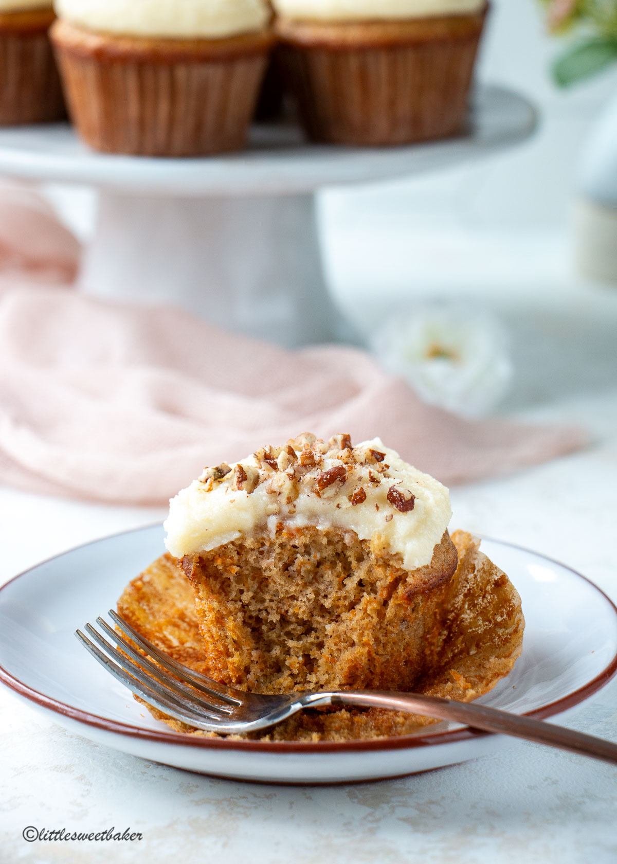 a carrot cake cupcake with cream cheese frosting with a bite missing