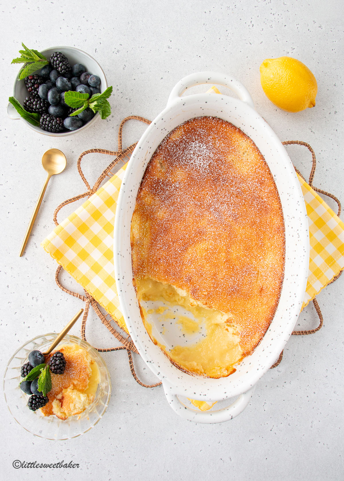 A dish of lemon pudding cake with a serving in a bowl.