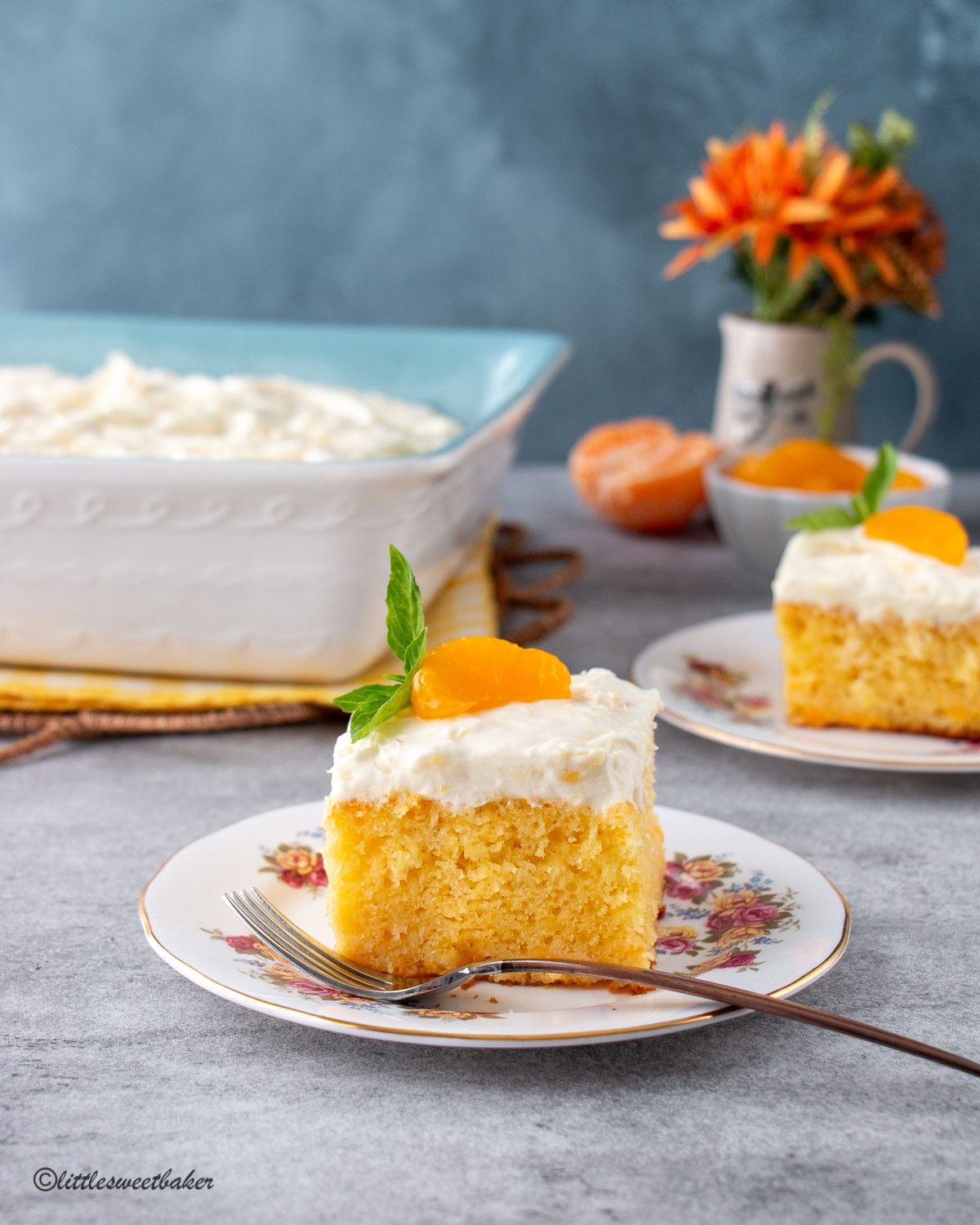 A slice of mandarin orange topped with pineapple frosting on a vintage plate.