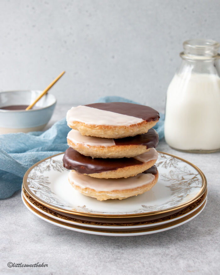 A stack of black and white cookies on a stack of gold and white plates.