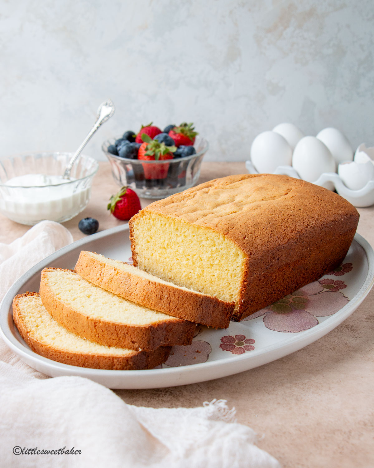 A loaf of egg yolk cake on a floral plate with a few slices cut