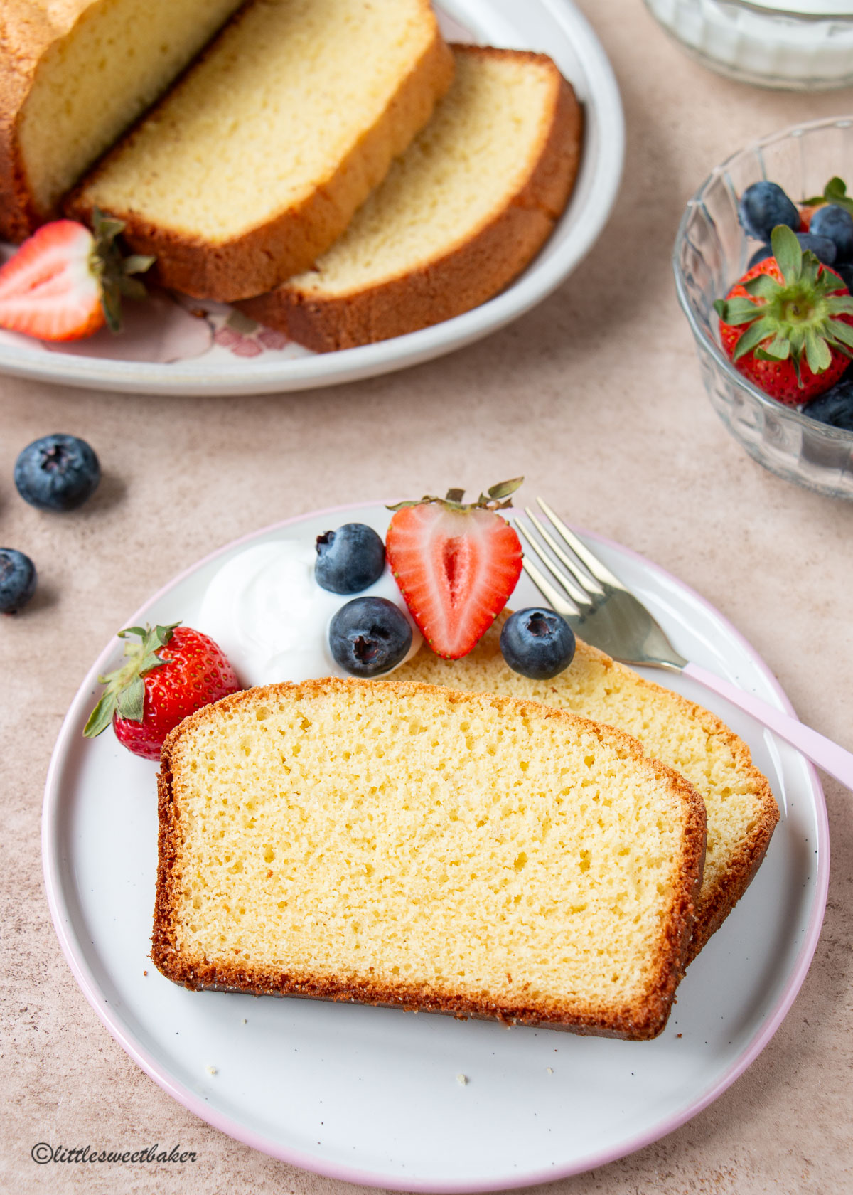 two slices of leftover egg yolk cake on a plate with a dollop of yogurt and berries.