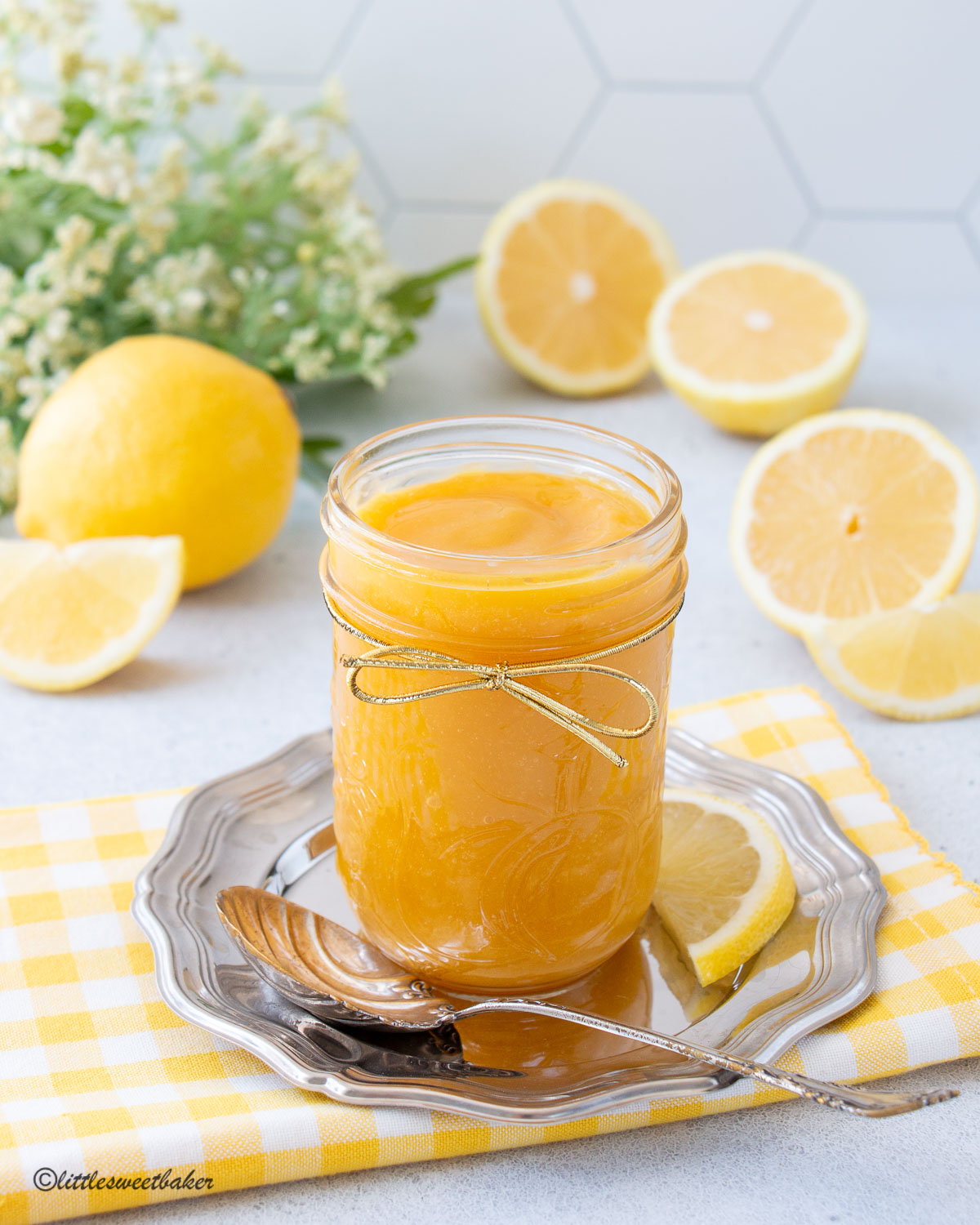 A jar of honey lemon curd on a small silver plate with spoon.