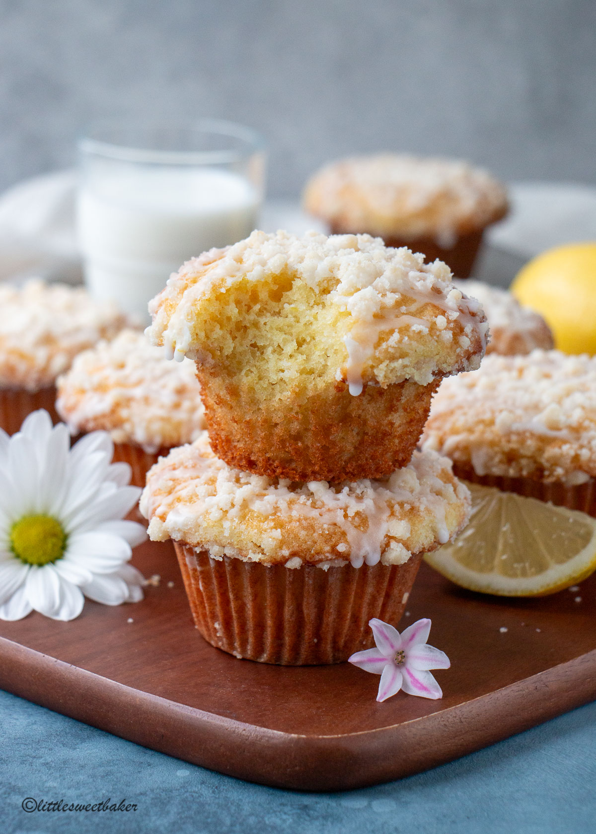 Two lemon muffins stack on top of one another with a bite taken out of the top one.