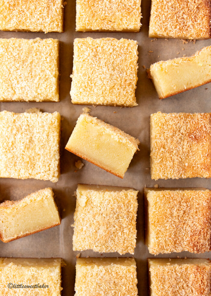 butter mochi cake squares arranged on parchment with 3 turned on its side