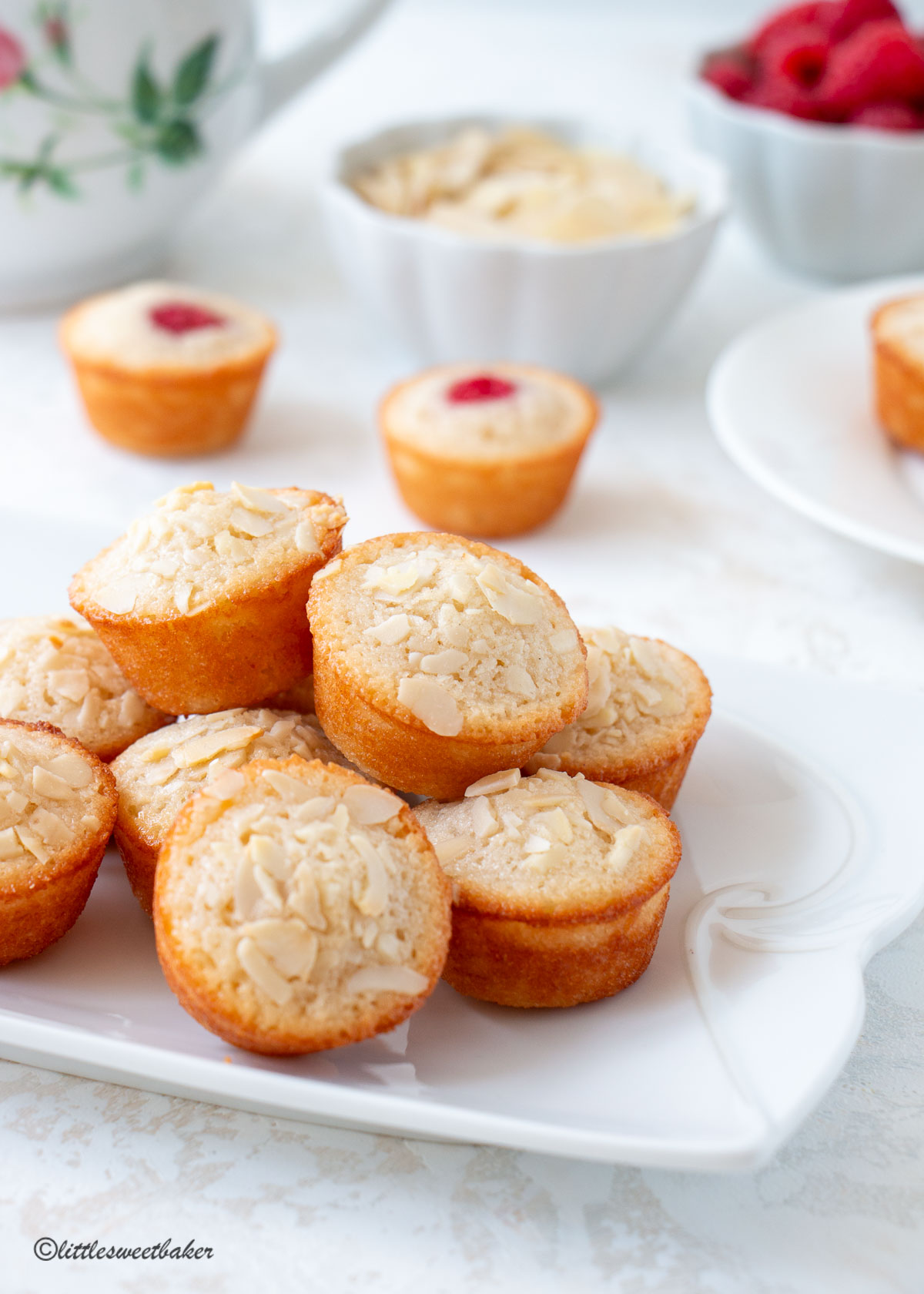 A stack of financier cakes topped with almonds on a white plate.