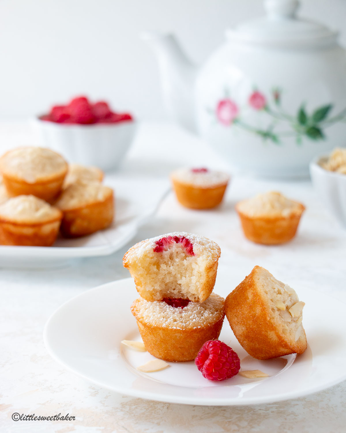 Three financier cakes on a plate with a bite taken out of one of them.