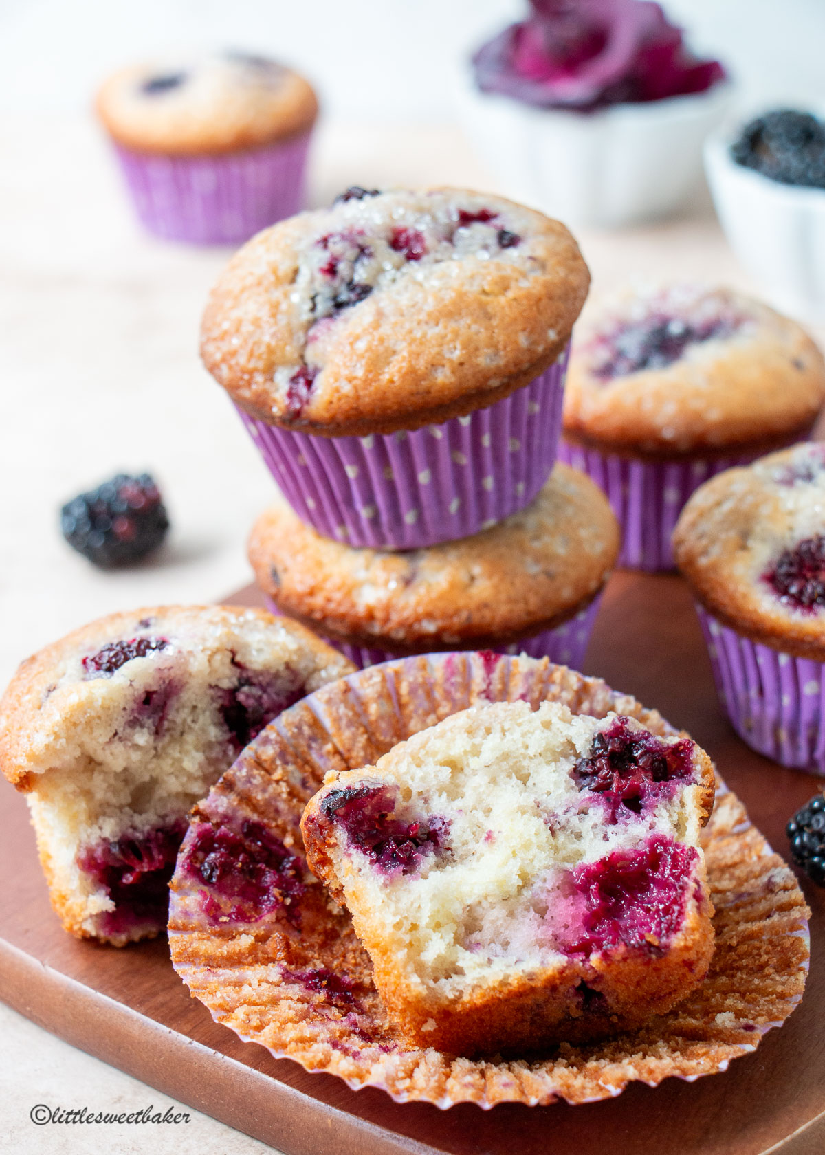 A blackberry muffin broken in half with two stacked behind it.