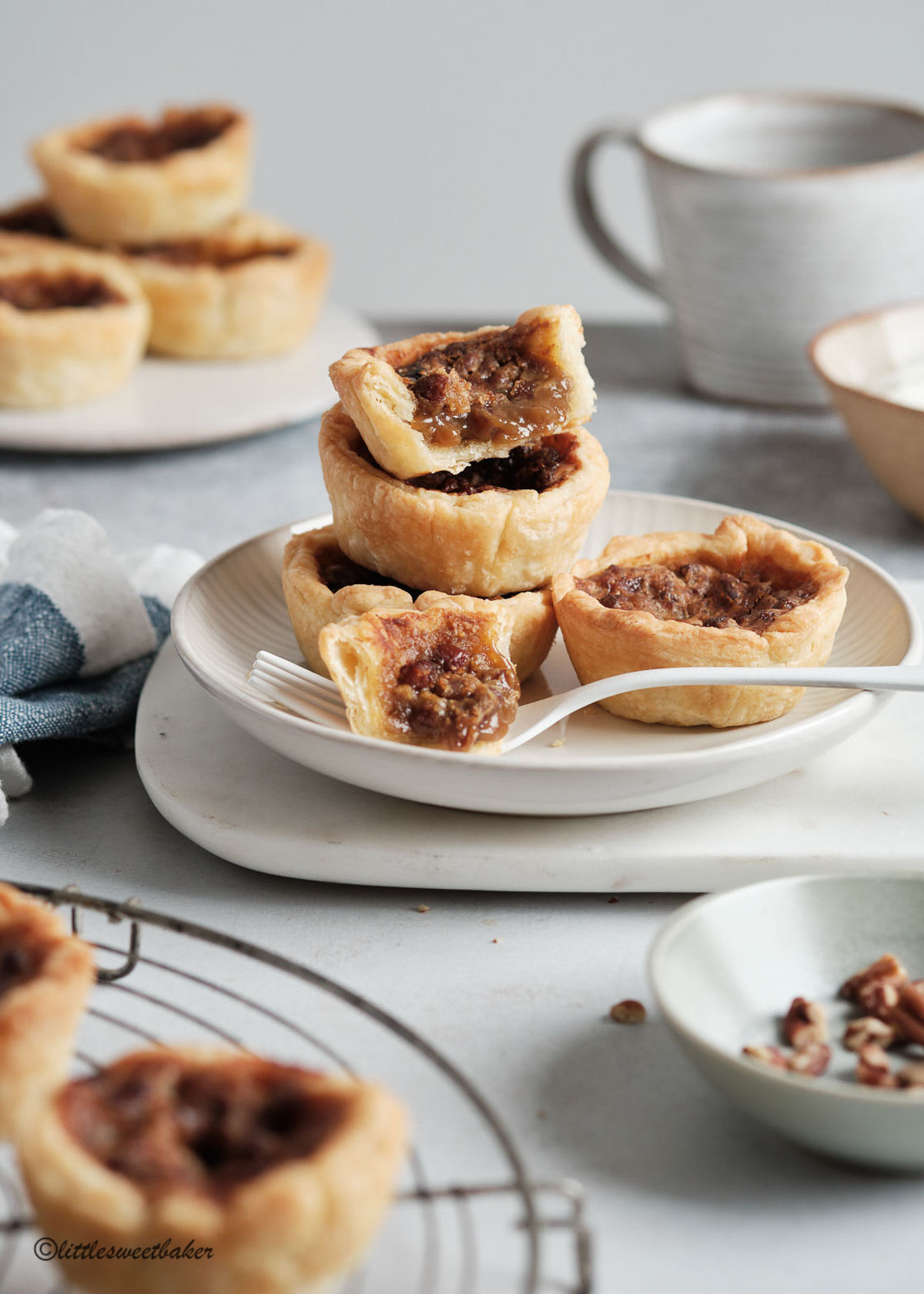 Four butter tarts on a plate with one partially eaten.