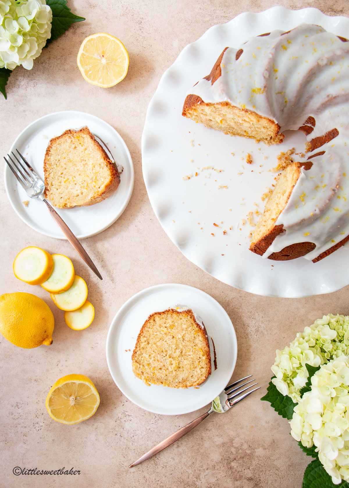 A glazed lemon zucchini cake on a cake stand with two slices on plates.