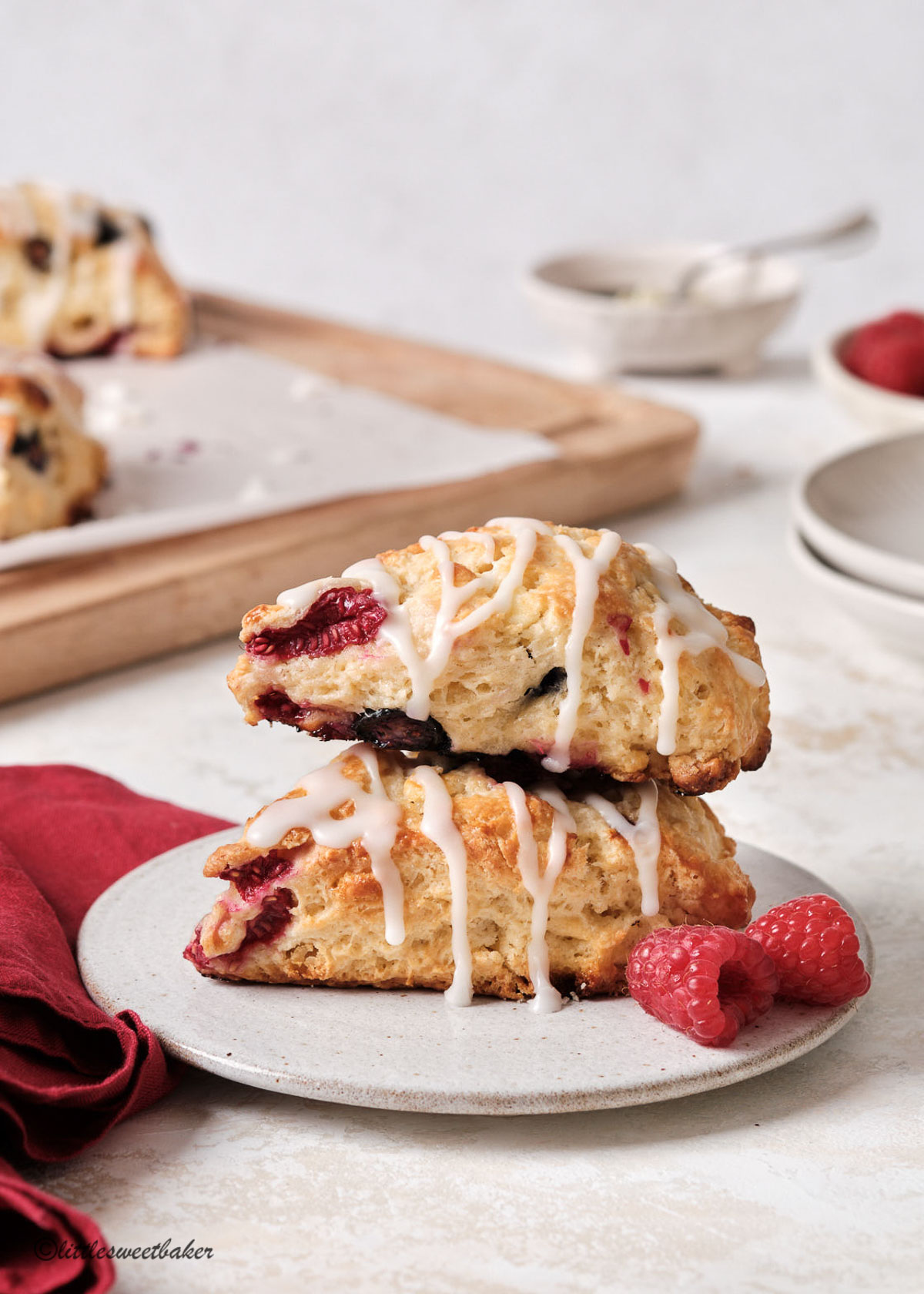 two glazed berry scones on stacked on a speckled plate