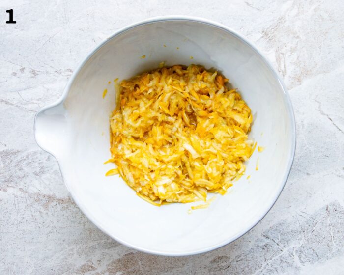 A mixing bowl of grated zucchini, sugar, lemon zest, and vanilla.