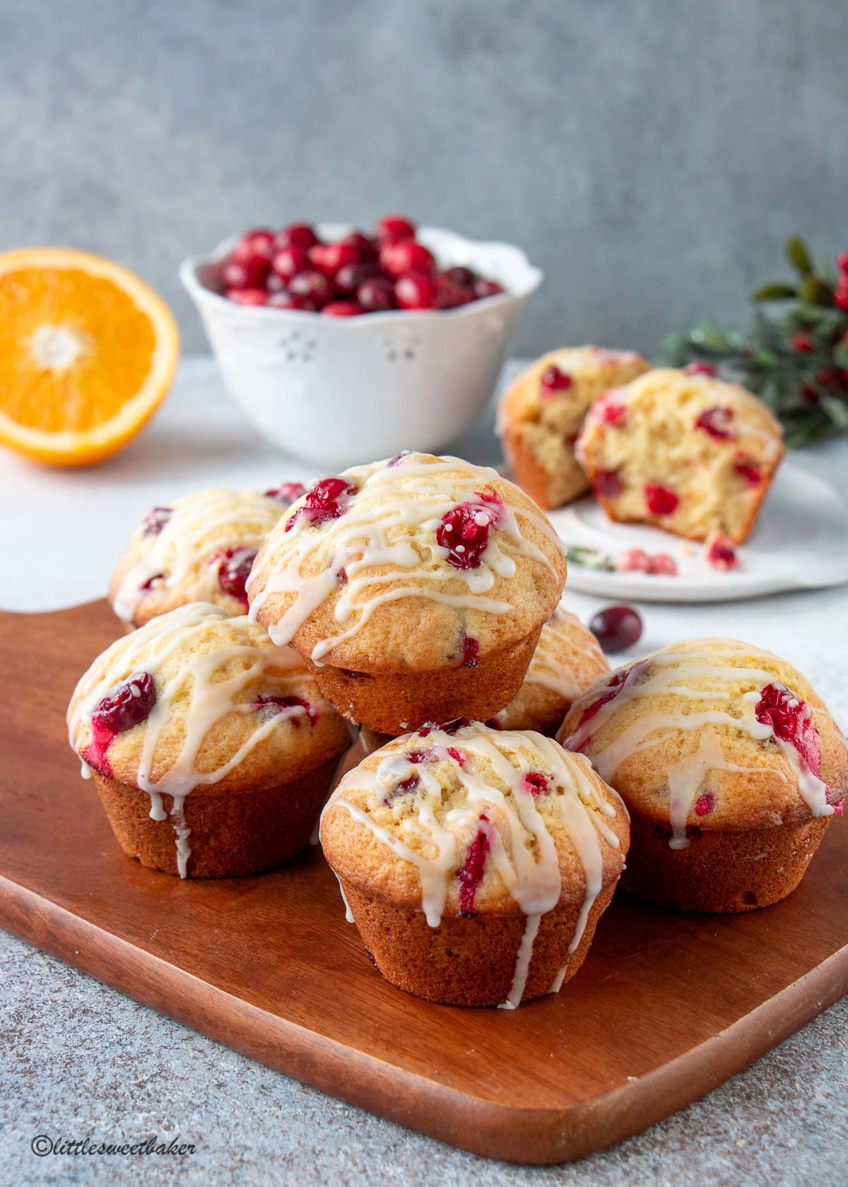 Orange cranberry muffins on a wooden cutting board.