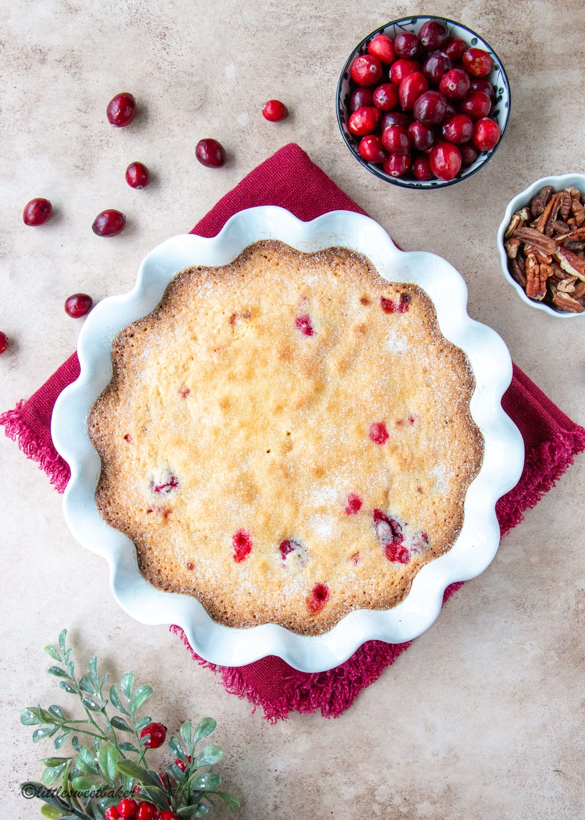 A Nantucket cranberry pie in a white ruffled pie plate on a crimson napkin.