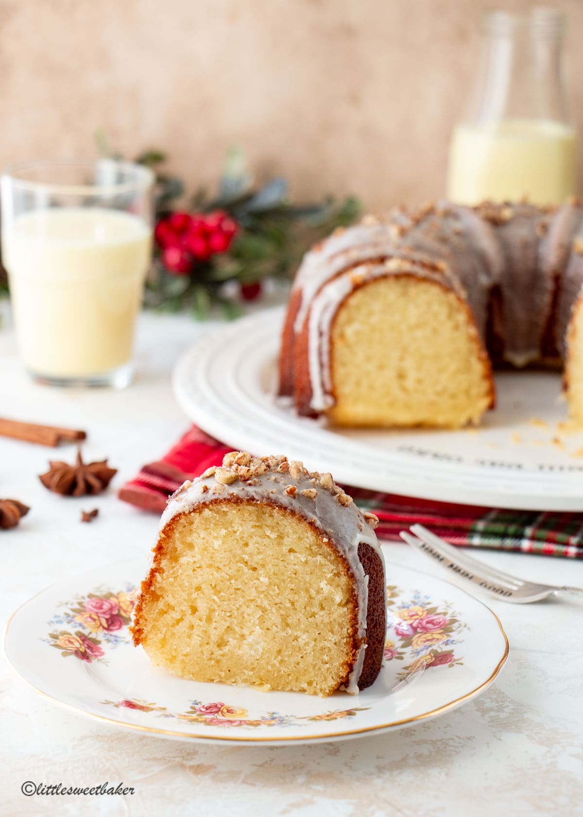 A glazed eggnog cake topped with nuts on a rose vintage plate.