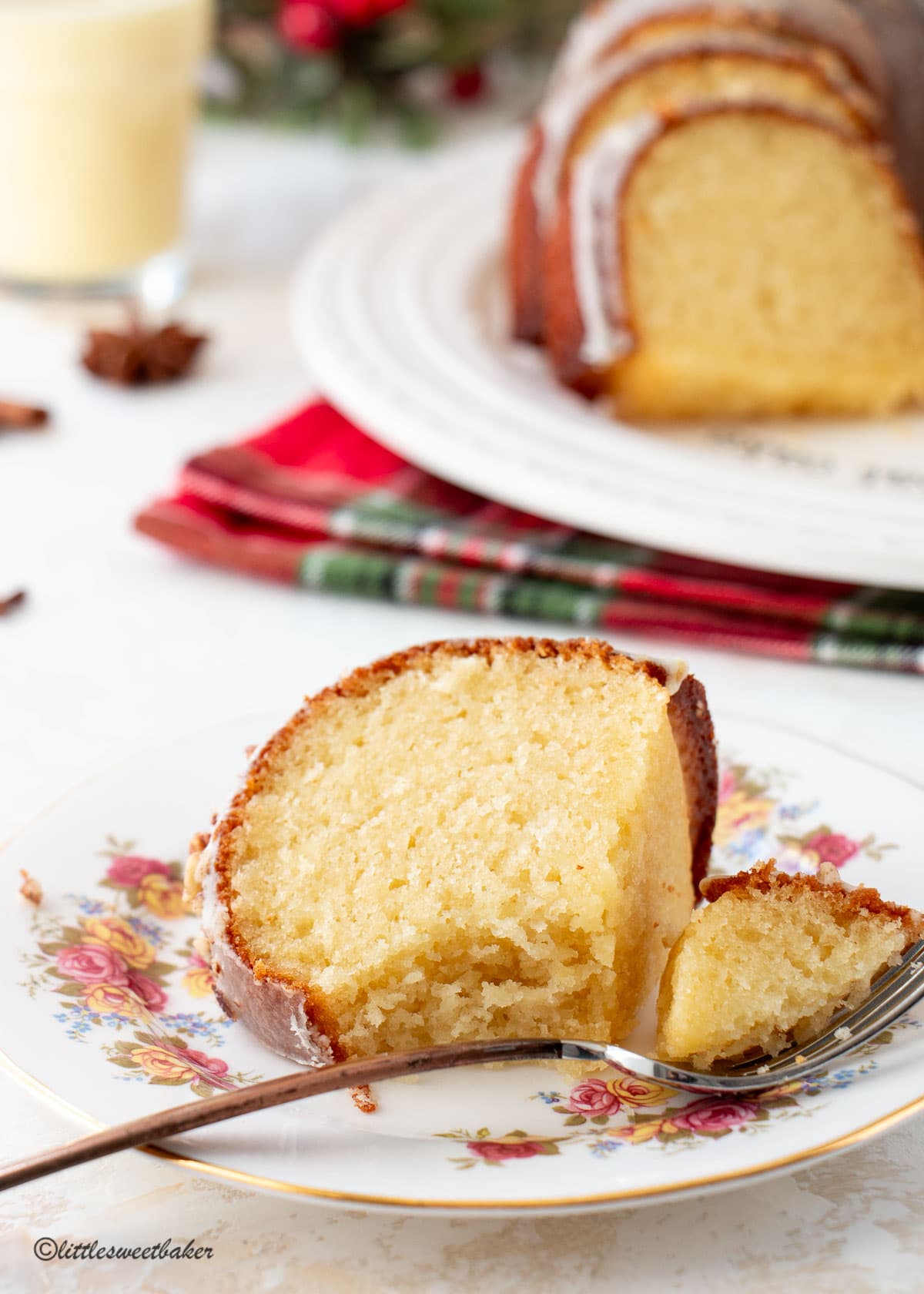 A slice of eggnog cake on a plate with a piece on a fork.