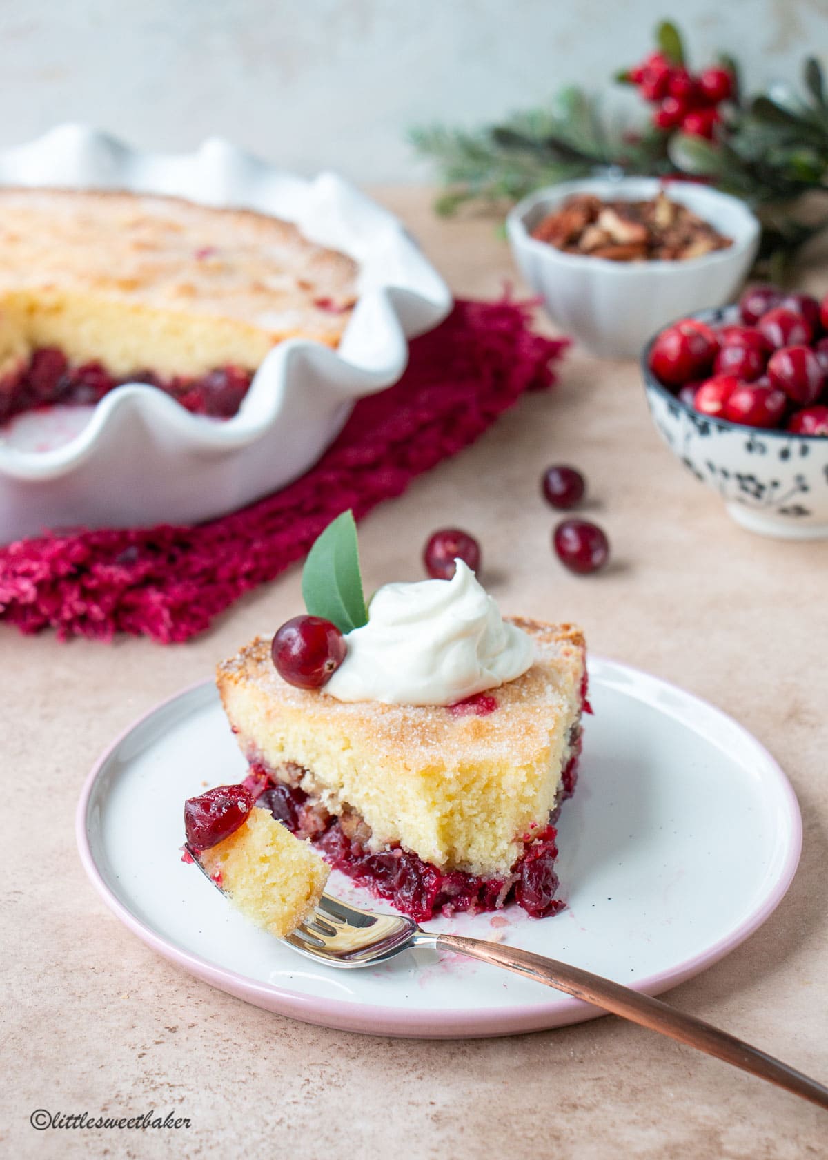 A slice of Nantucket cranberry pie on a pink and white plate with a piece of the pie on a fork.