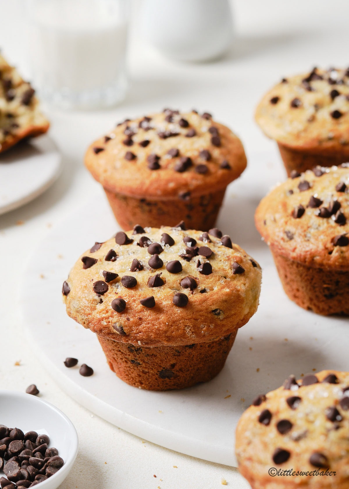 Beautiful bakery-style chocolate chip muffins in a white marble board.