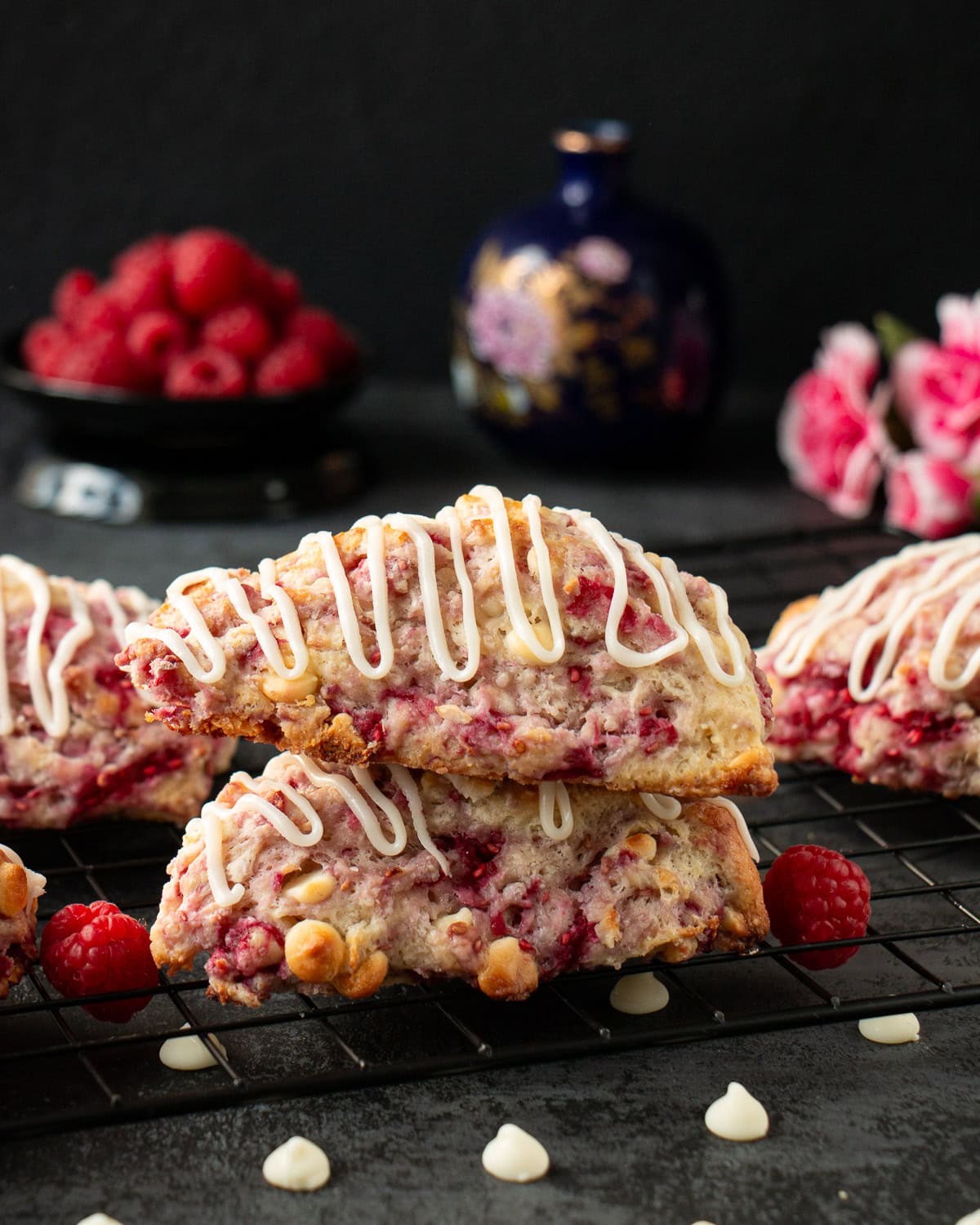 Two raspberry white chocolate scones stacked on top of one another on a cooling rack.