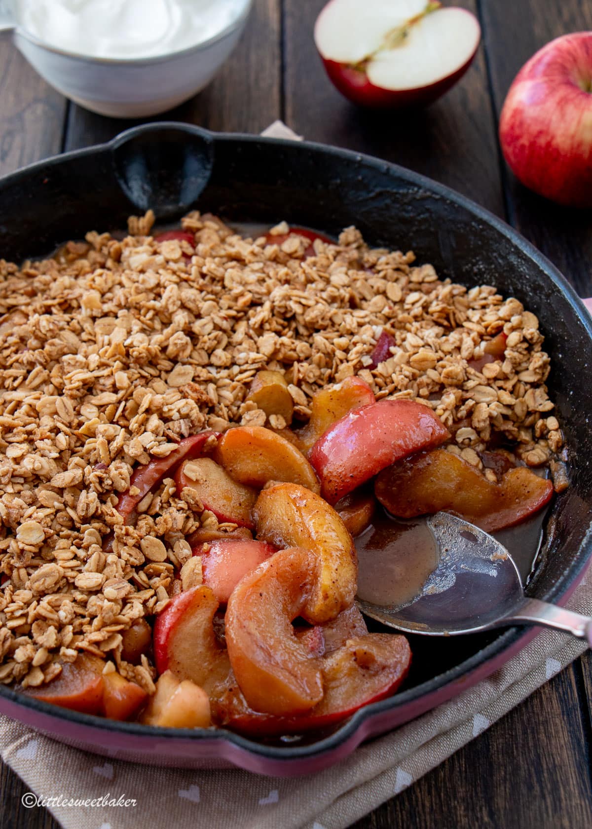 Stovetop apple crisp in a cast iron skillet with a serving spoon.