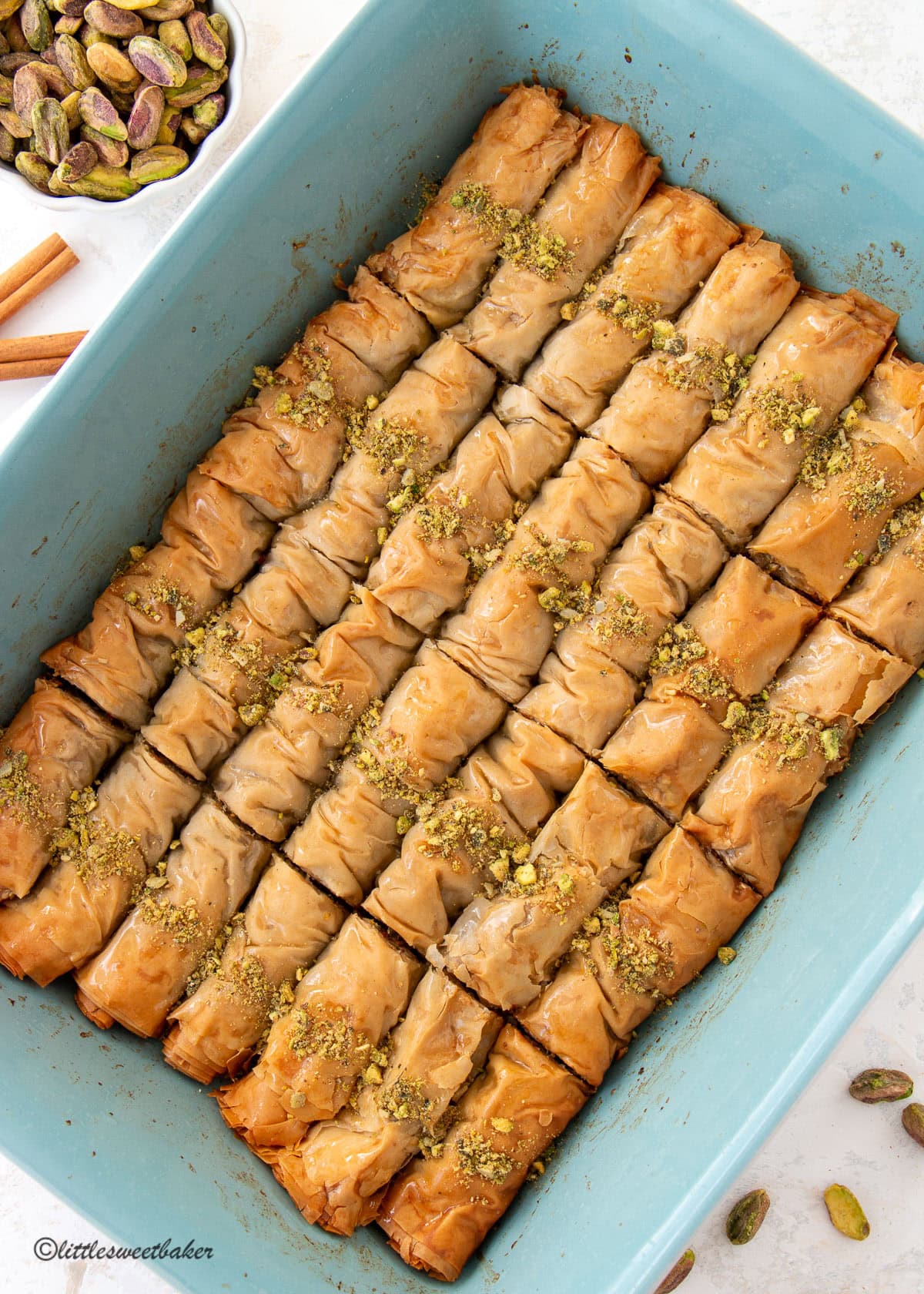 A ceramic baking pan of pistachio baklava rolls.