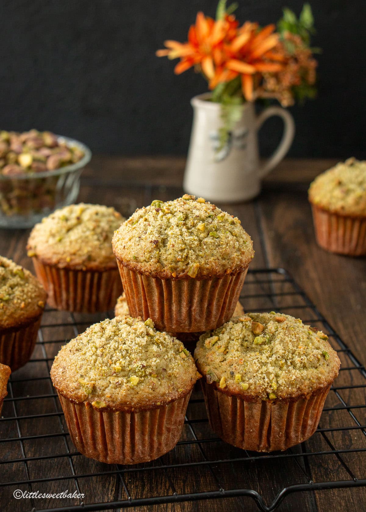 Pistachio muffins on a black wire cooling rack.